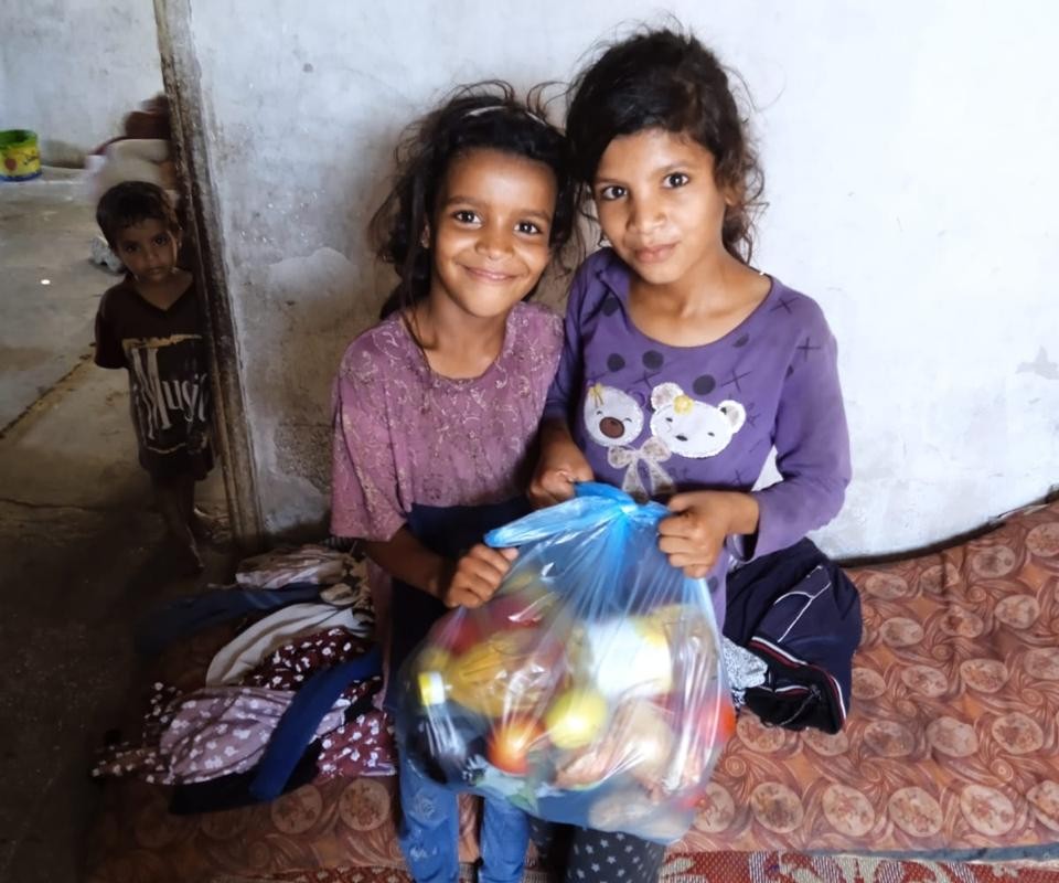Two children hold a package of food aid.